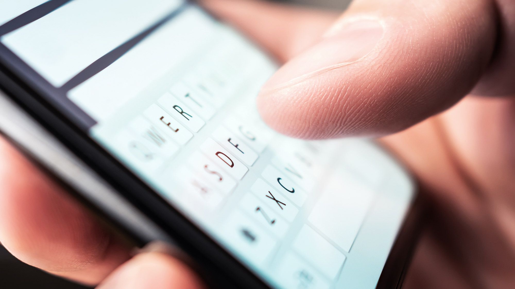 mobile phone screen with imessage open and someone typing at a keyboard from Shutterstock