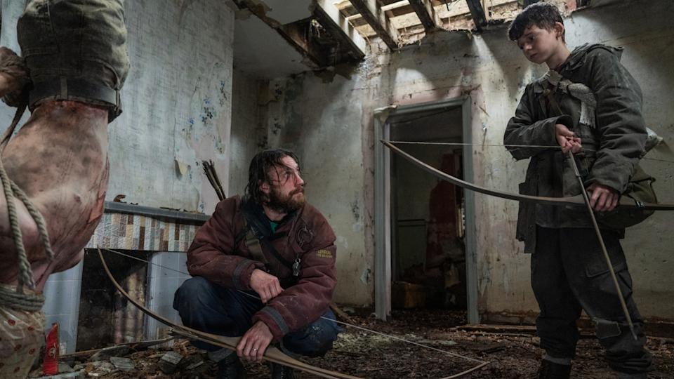 Aaron Taylor-Johnson looks up at Alfie Williams as they stand by a hanging Infected in 28 Years Later