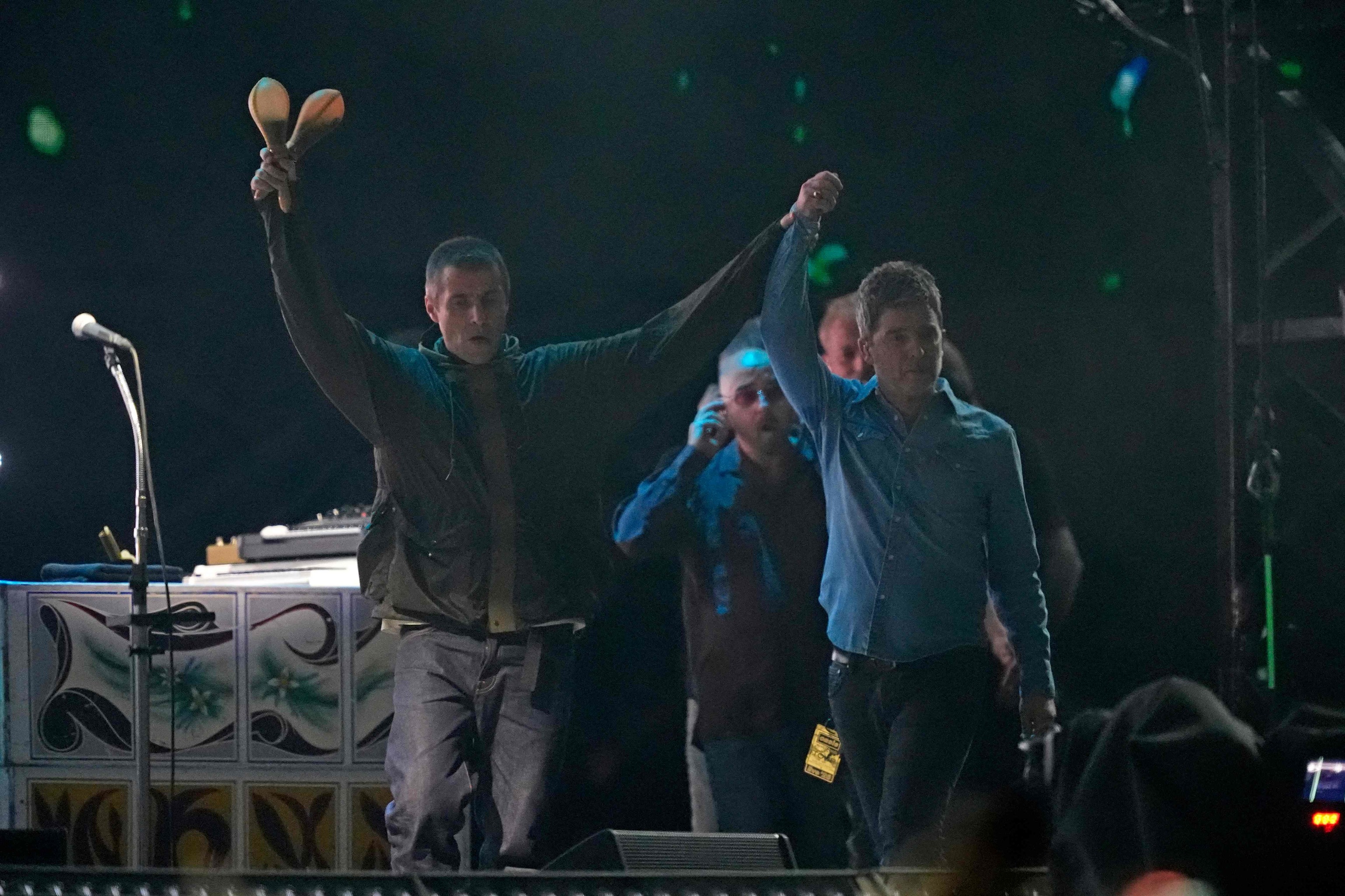Liam y Noel Gallagher saludan en el concierto de Oasis en Cardiff.