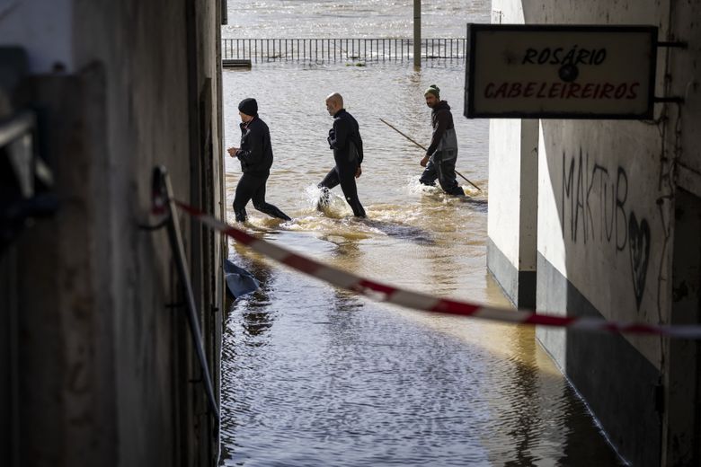 Volunteers navigate through a flooded street in Portugal.