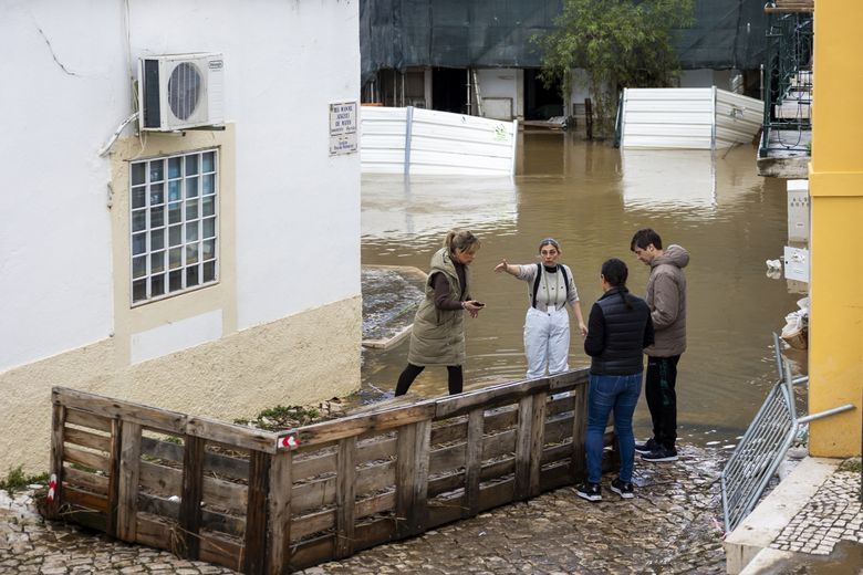 Residents chat near a flooded street in Alcacer do Sal, Setubal, Portugal.