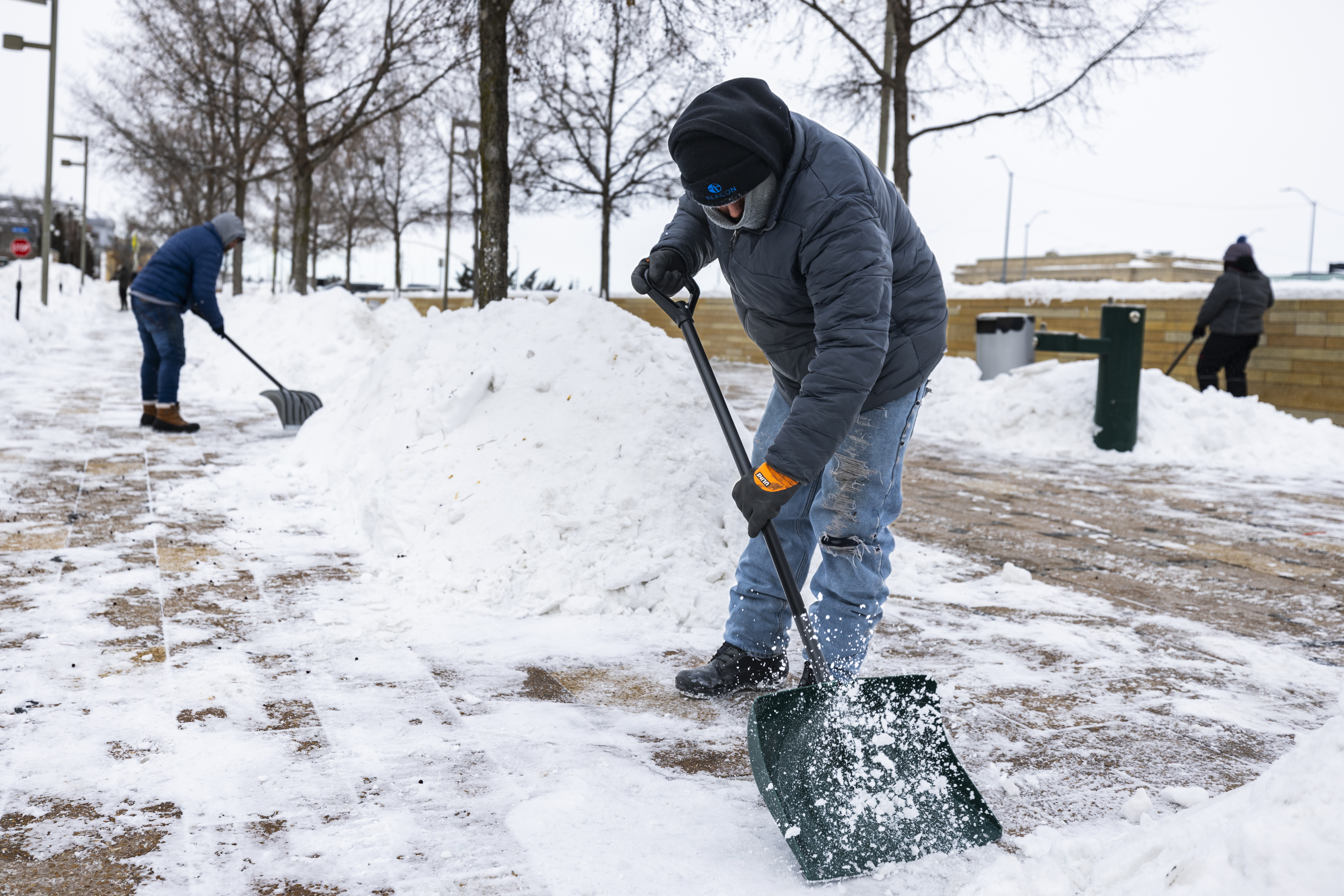 Jornaleros quitan nieve de la acera en el centro de Des Moines, Iowa, el lunes mientras las temperaturas caen a ocho grados bajo cero Fahrenheit.