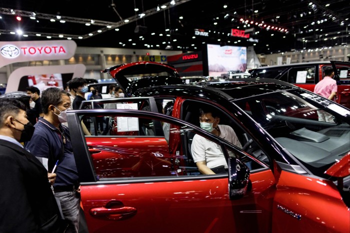 Los visitantes examinan el híbrido Corolla Cross HEV GR Sport de Toyota en un salón del automóvil
