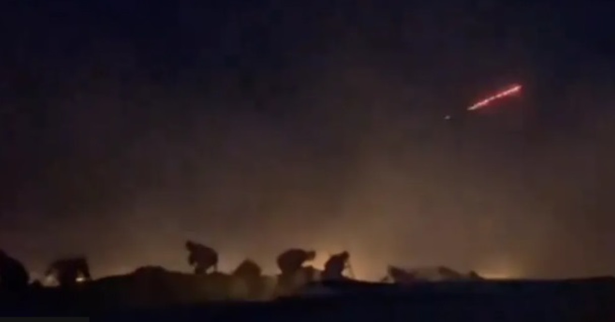 Una imagen de un vídeo de Al Jazeera, filmada cerca de la parte trasera del convoy, muestra a personas escondidas detrás de vehículos.  También hay un destello de luz roja.  Imagen Al Jazeera