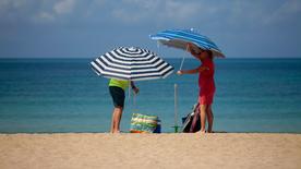 España, Palma de Mallorca: Una pareja instala sombrillas en la playa de Palma de Mallorca.
