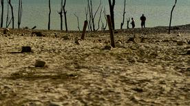 La gente camina a lo largo de las orillas del embalse de Yesa, afectado por la sequía, en el norte de España, en un día soleado de verano.