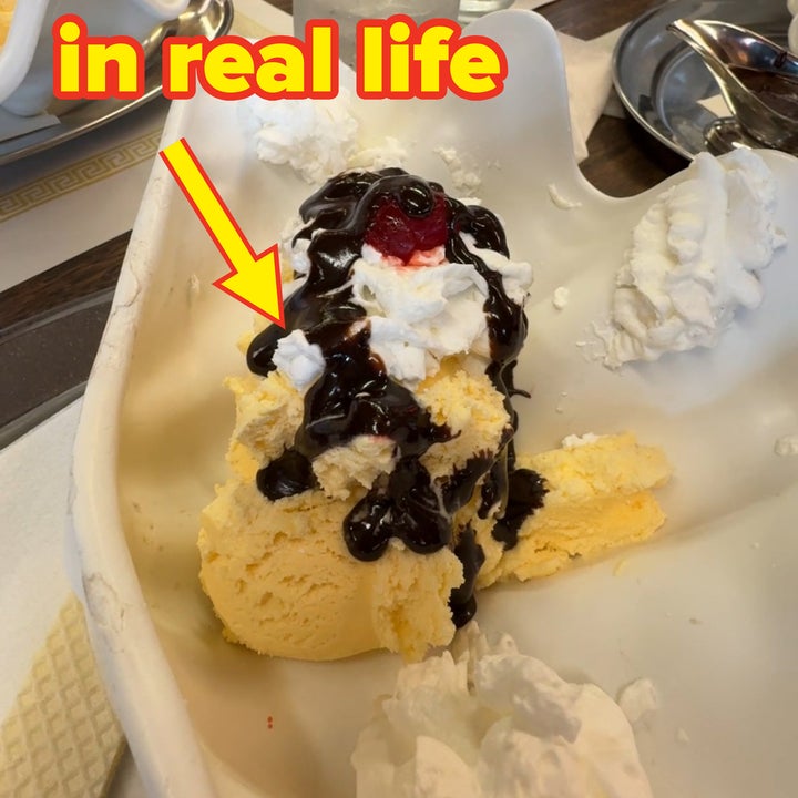 Un helado a medio comer con helado de vainilla, crema batida, sirope de chocolate y una cereza encima, sobre una mesa con vasos de agua y otros platos de helado
