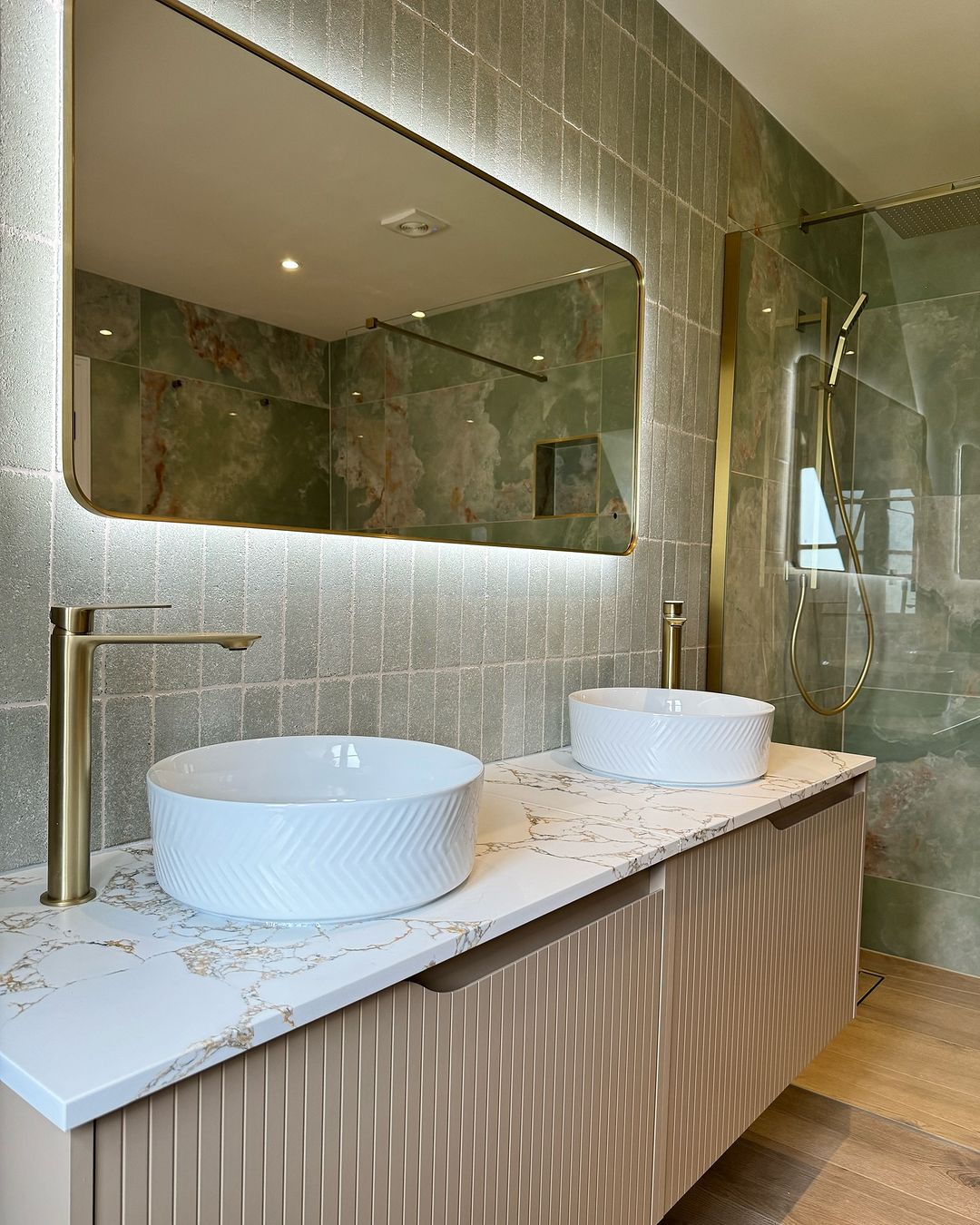 El baño de la pareja luce clásico con encimeras de mármol y lavabos blancos.