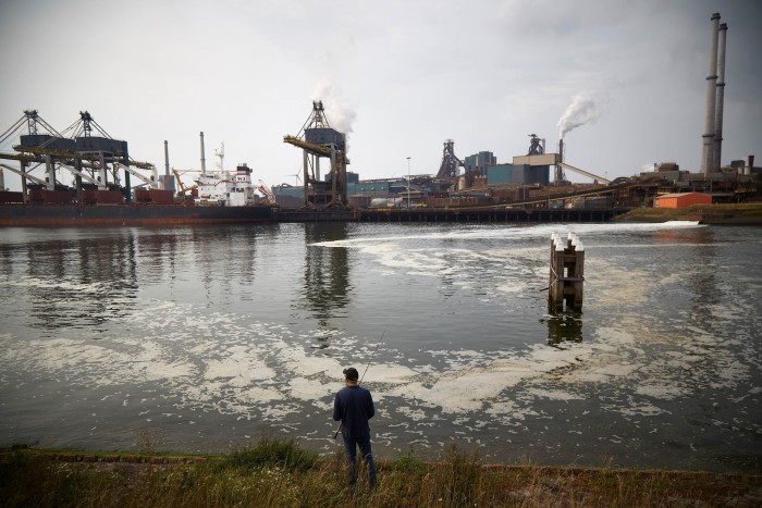 Un hombre pesca en un canal junto a una planta de Tata Steel en los Países Bajos