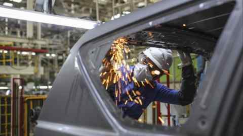 Un trabajador trabaja en un vehículo en la planta de Toyota en Bidadi, Karnataka, India