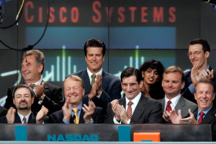 Un grupo de ejecutivos se encuentra en la sala de operaciones del Nasdaq bajo un cartel de Cisco