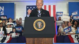 El presidente de Estados Unidos, Joe Biden, sube a un escenario en un evento de campaña, aprieta el puño y sonríe a la cámara.