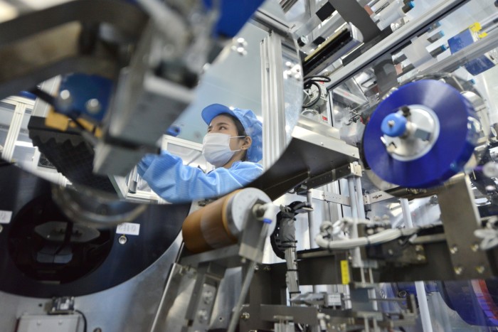 Un trabajador de una fábrica se ve reflejado en un espejo en una planta de producción de baterías de iones de litio en la provincia oriental china de Zhejiang