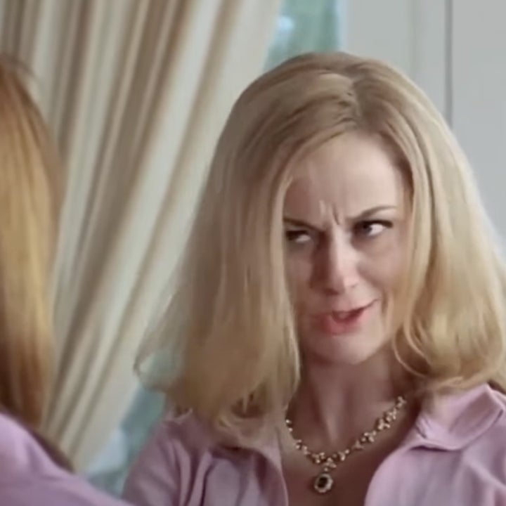 Amy Poehler en una escena de "Chicas malas" De pie en un lugar cerrado con un collar y una blusa, haciendo una expresión humorística hacia otra persona.