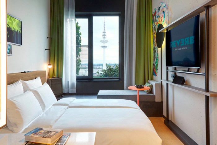 Una habitación de hotel con cama doble y vistas a la ciudad, incluida la torre de televisión a lo lejos.