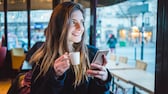 Mujer en la cafetería usando un teléfono inteligente