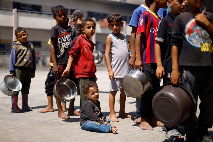 Niños palestinos hacen cola para recibir comida en Khan Younis, en el sur de la Franja de Gaza, a finales de junio