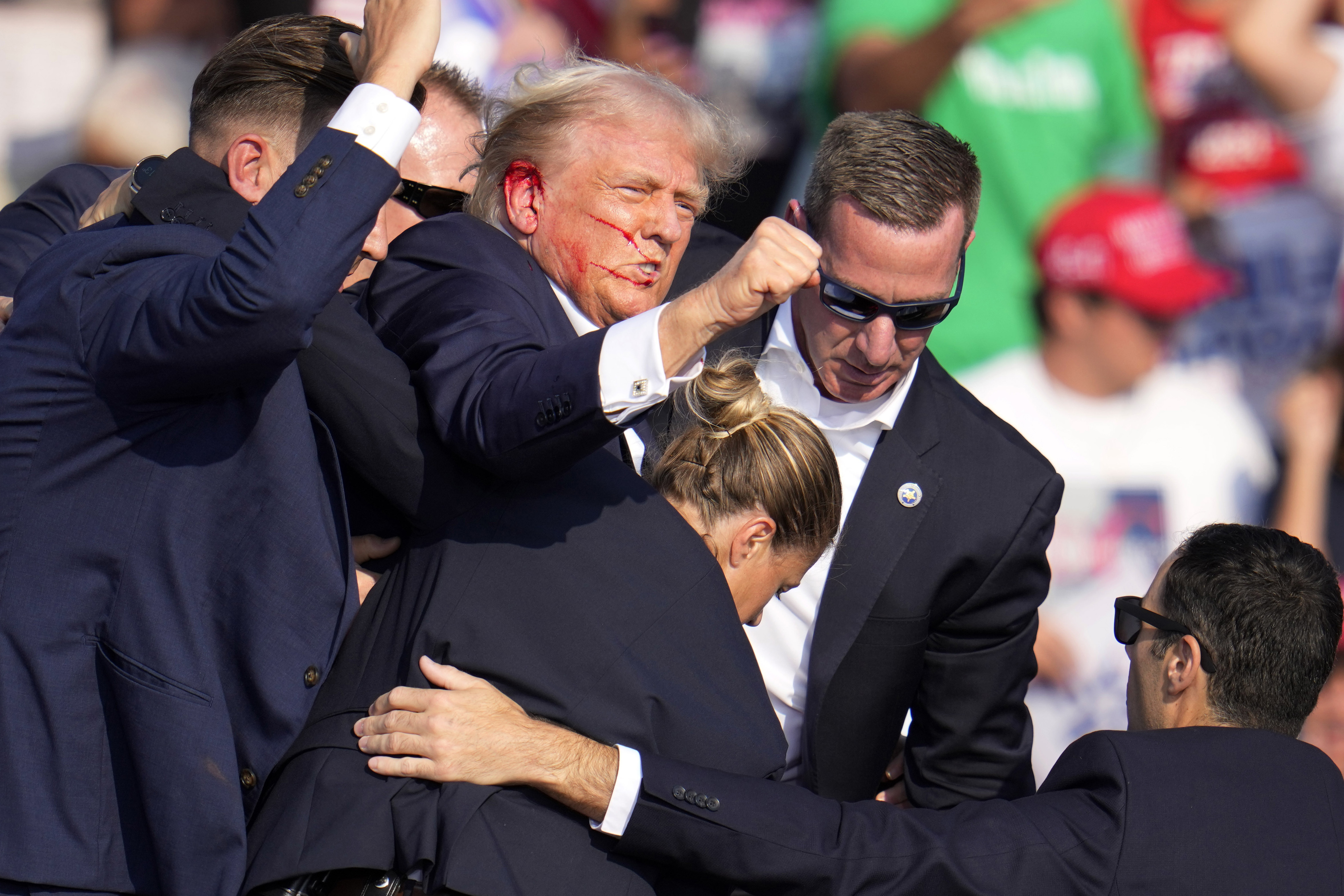 El candidato presidencial republicano y expresidente Donald Trump es ayudado a salir del escenario por el Servicio Secreto de Estados Unidos.
