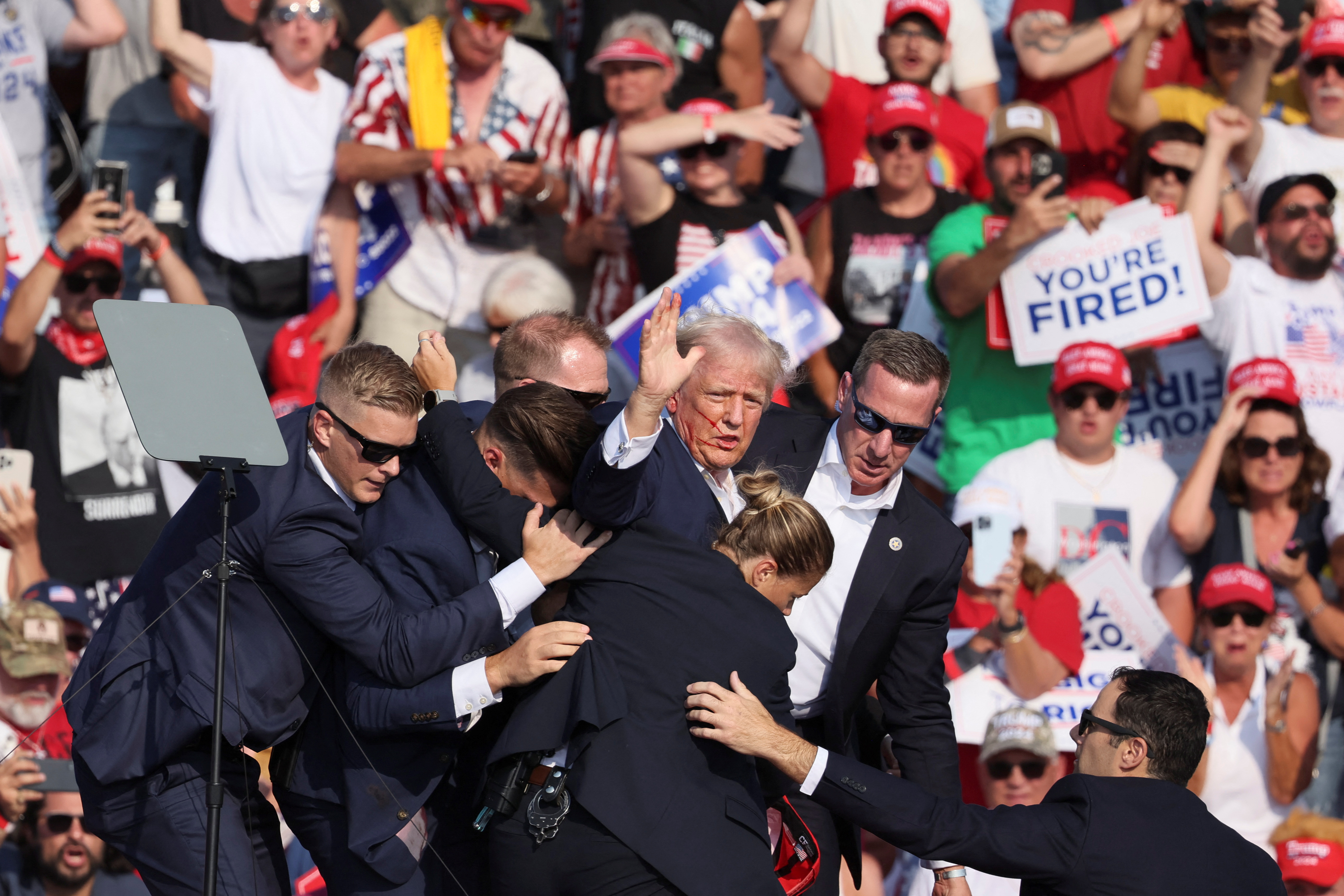 El candidato presidencial republicano y expresidente de Estados Unidos, Donald Trump, hace un gesto con la cara ensangrentada mientras es retirado por el personal del Servicio Secreto de Estados Unidos después de que le dispararan en la oreja derecha durante un mitin de campaña en Butler, Pensilvania.