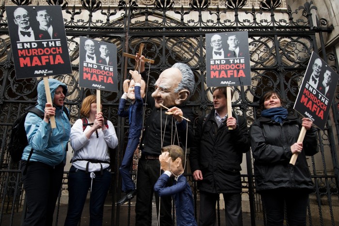 Manifestantes sostienen carteles y marionetas frente al Tribunal Superior en el centro de Londres en 2012 