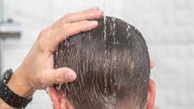 La cabeza de un hombre en la ducha, su cabello está mojado.