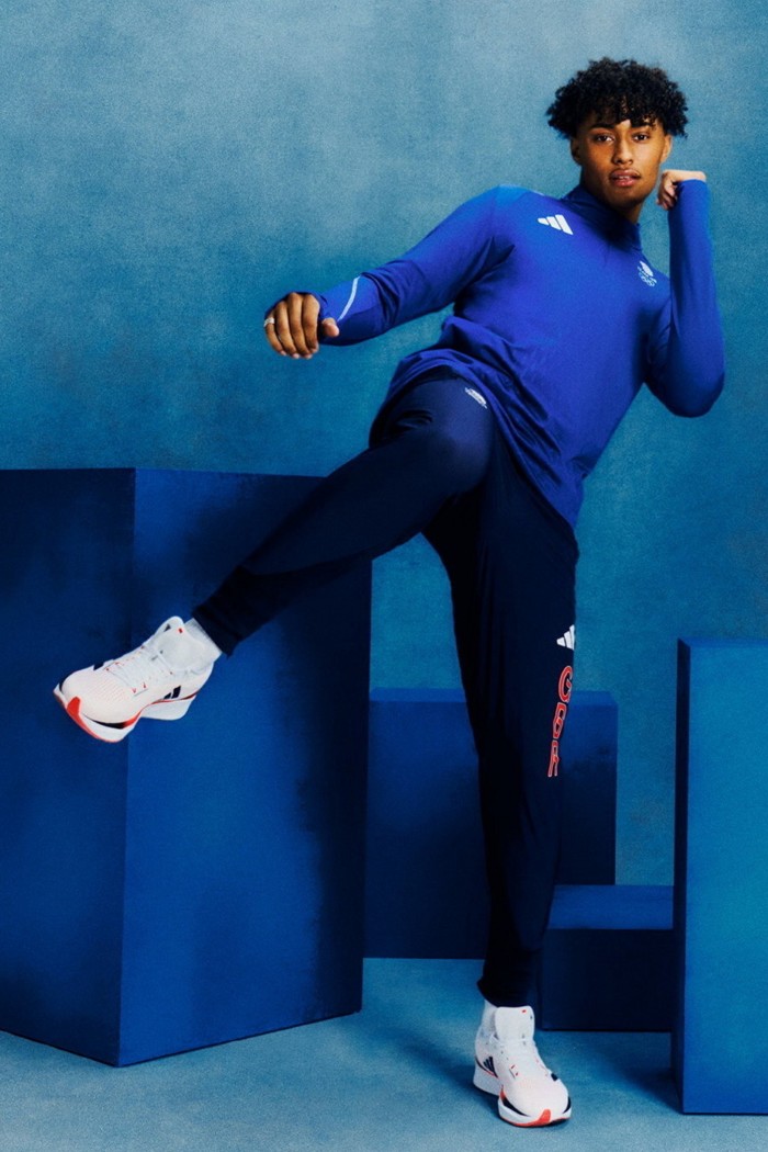 Un joven atlético, todo de azul y con zapatillas blancas, hace una pose de patada.