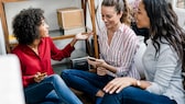 Grupo de mujeres jóvenes sentadas juntas y discutiendo cómo configurar permisos de aplicaciones