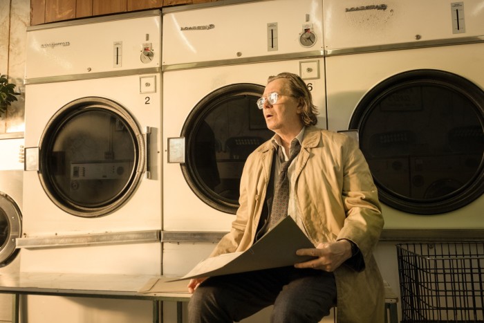 Un hombre mayor, desaliñado y con cabello gris se sienta en una lavandería.