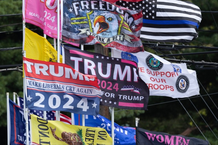 Los partidarios de Donald Trump colocan varias banderas en el exterior de un mitin en Harrisburg, Pensilvania.