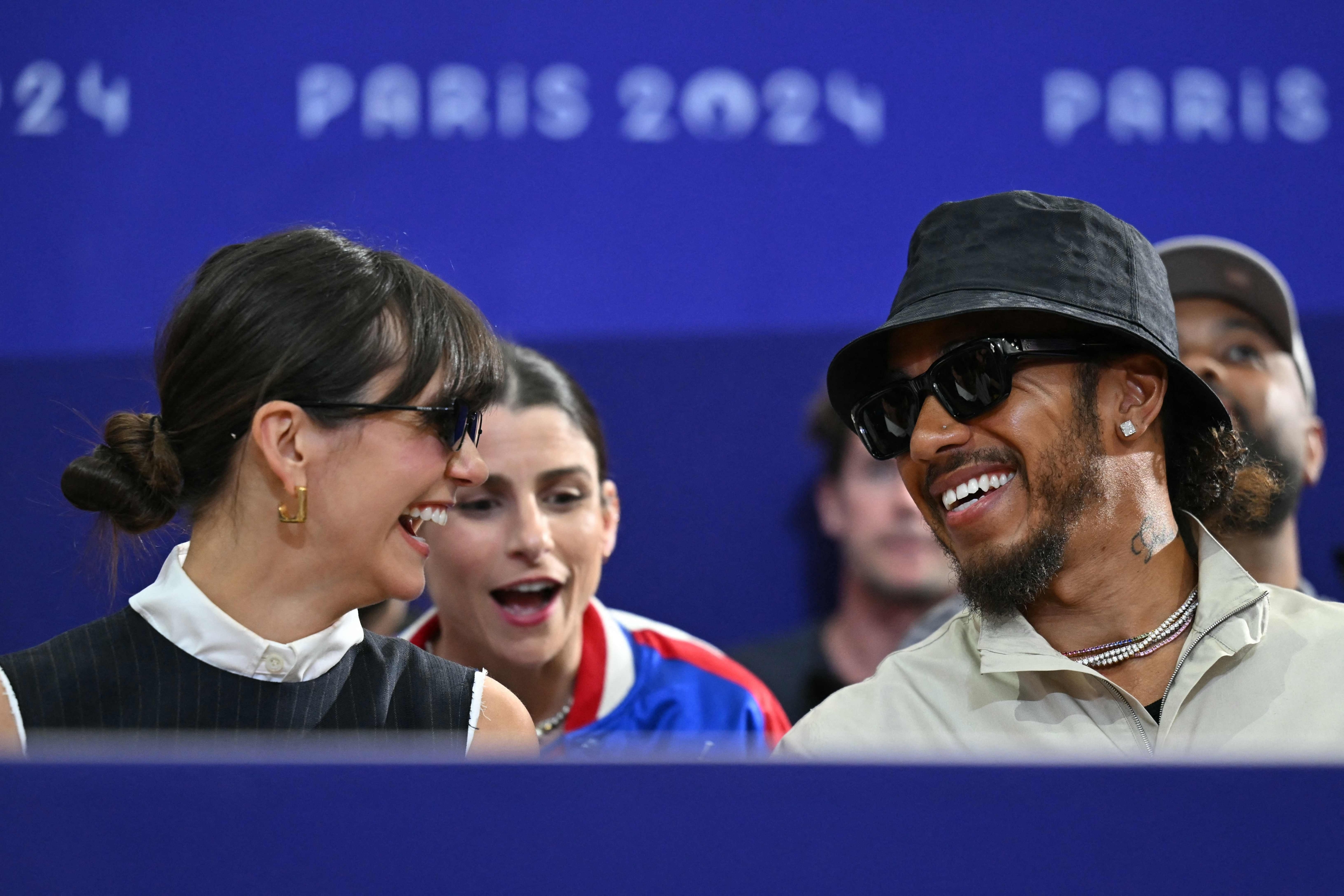 La modelo canadiense Nina Dobrev (L) y el piloto británico de F1 de Mercedes, Lewis Hamilton, asisten a la pelea por la medalla de bronce del equipo de florete masculino entre EE. UU. y Francia durante los Juegos Olímpicos de París 2024 en el Grand Palais de París, el 4 de agosto de 2024. (Foto de Fabrice COFFRINI/AFP)