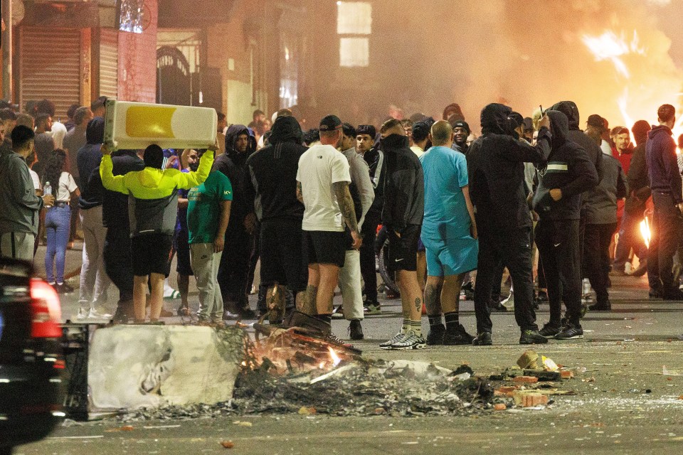 Escena en Harehills donde la gente incendia vehículos en un motín