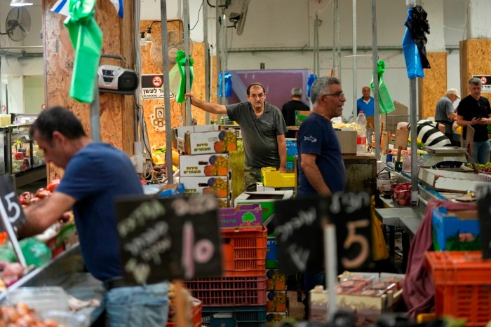 Los vendedores venden frutas y verduras en un mercado en Haifa, Israel.