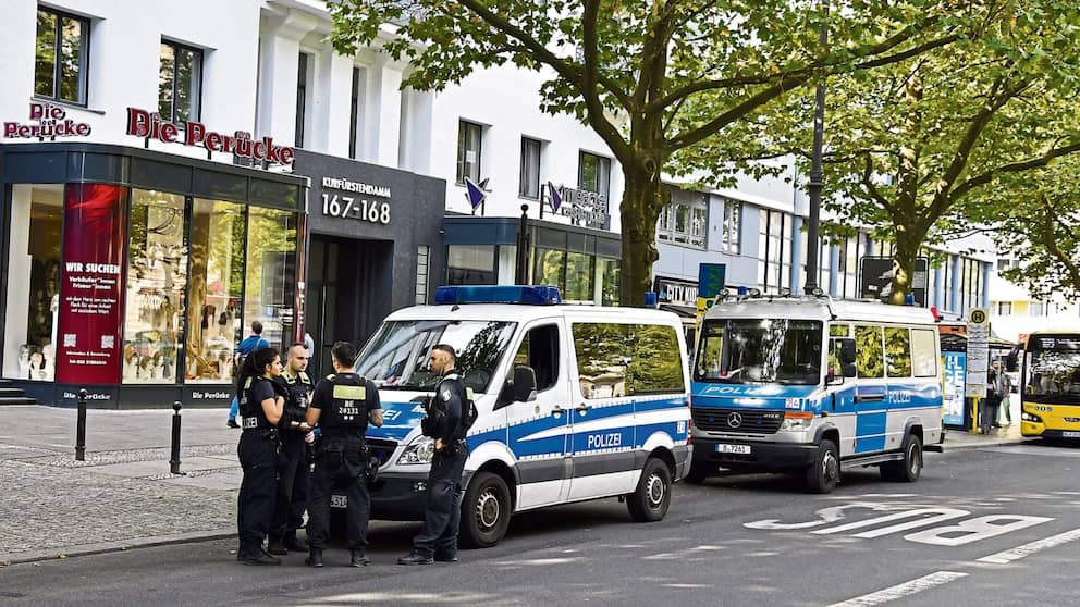 Dos patrullas de policía están estacionadas frente a las casas, con agentes de policía delante de ellos.