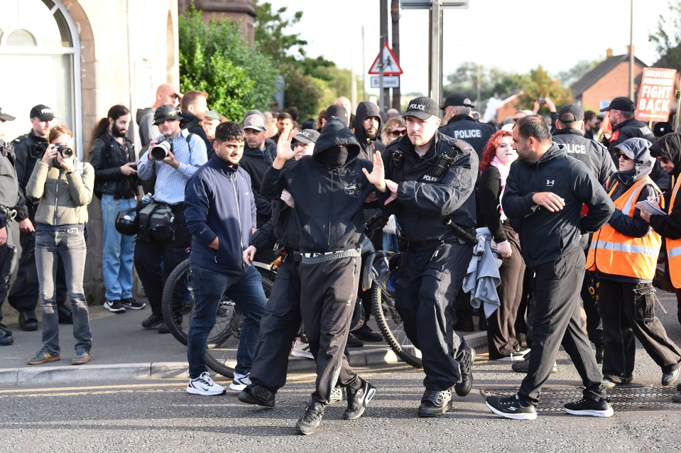 La policía retira a un manifestante que se negó a quitarse la mascarilla frente al Centro de Refugiados de Merseyside en Liverpool