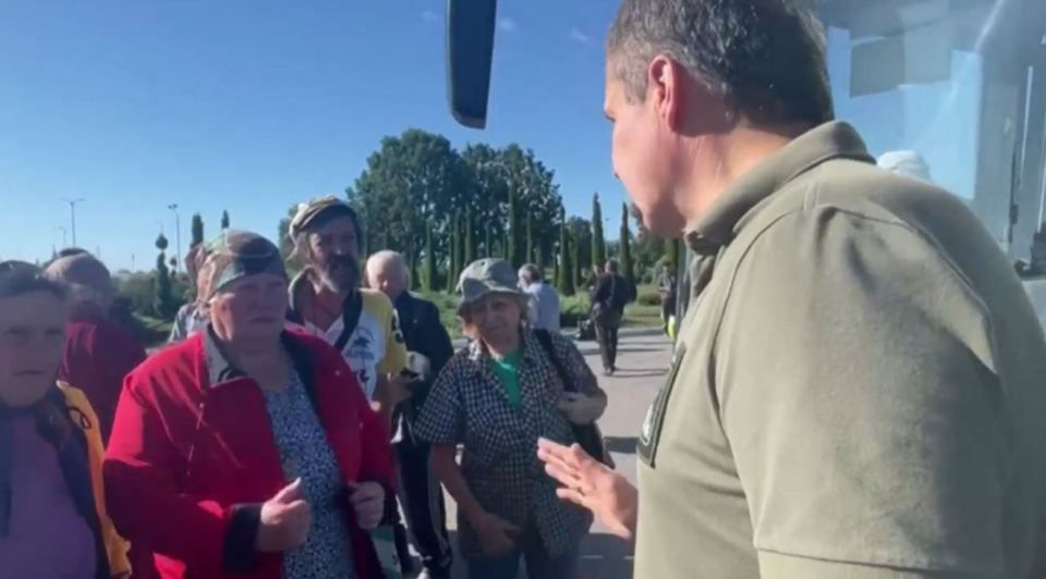 Un funcionario habla ante la multitud cerca de los autobuses.