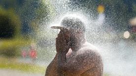 Un hombre se refresca bajo una ducha fría en un lago para nadar.