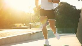 Torso de un hombre corriendo bajo el sol de la mañana de verano.