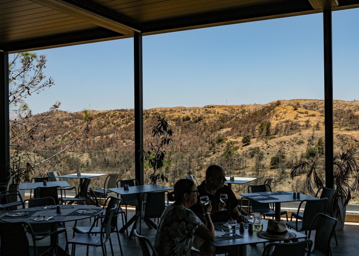 Con vistas a las cimas de las colinas carbonizadas, una pareja bebe vino.