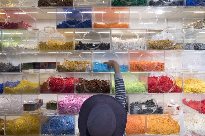 Un niño alcanza los ladrillos Lego de un estante.