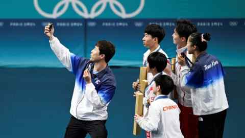 Los medallistas de Corea del Sur, Corea del Norte y China se toman una selfie con un teléfono proporcionado por Samsung