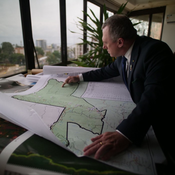 Un hombre con un traje azul oscuro señala un área marcada en un mapa.