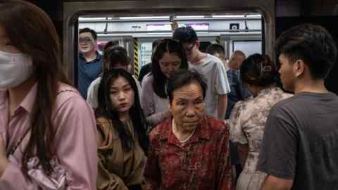 Dos mujeres, una joven y otra mucho mayor, salen de un abarrotado tren del metro de Pekín.