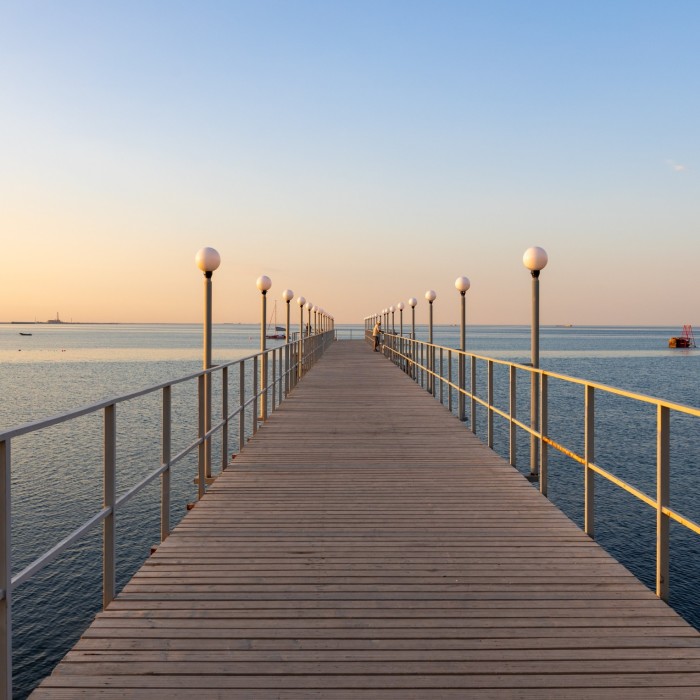 Un embarcadero de madera que sobresale hacia el mar bajo una puesta de sol.