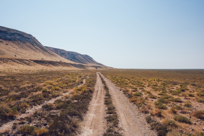 Paisaje de camino estrecho con pasto seco y formaciones rocosas en un clima sin nubes 