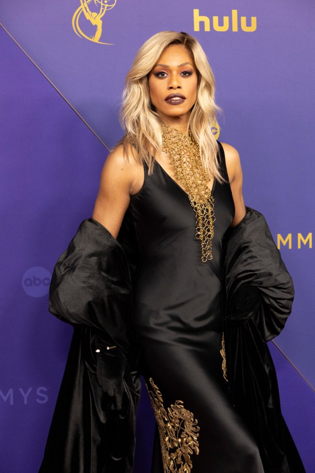 Laverne Cox camina por la alfombra con un impresionante vestido negro bordado con accesorios dorados a juego.