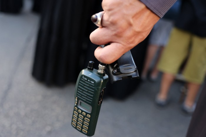 Un hombre sostiene un dispositivo walkie talkie después de quitarle la batería durante el funeral 