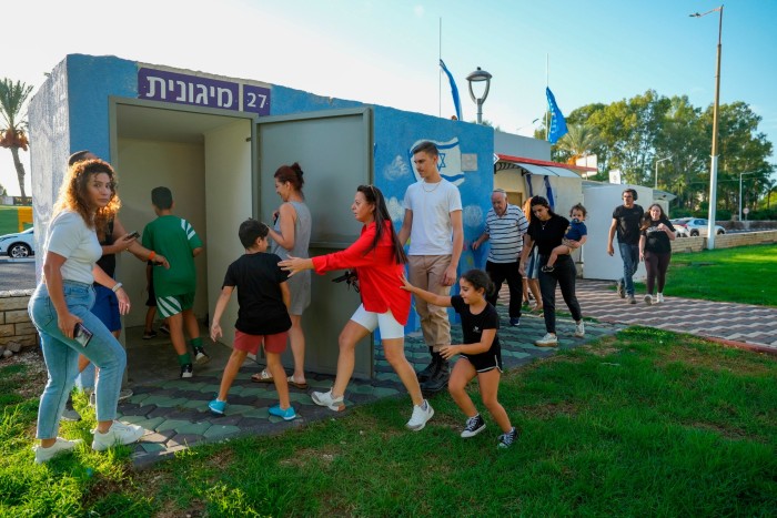 La gente en Nahariya, en el norte de Israel, se pone a cubierto mientras una sirena advierte sobre cohetes disparados desde el Líbano el jueves