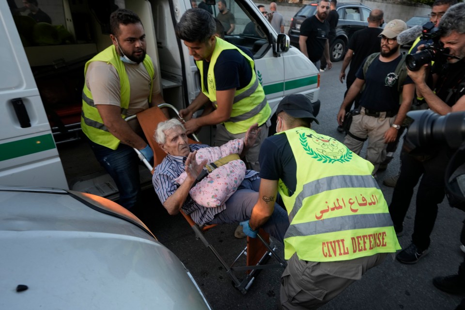 Los trabajadores de protección civil llevan a un anciano que huyó del sur cuando llega a una escuela convertida en refugio en Beirut