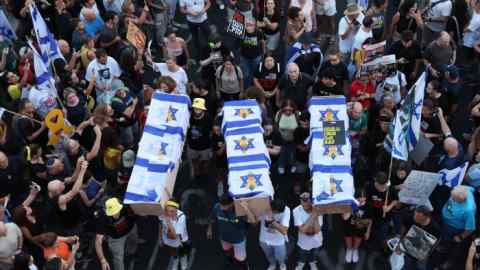 Manifestantes portan ataúdes simbólicos envueltos en banderas israelíes, que representan a seis rehenes israelíes cuyos cuerpos fueron recuperados de la Franja de Gaza. La gente sostiene banderas, carteles y pancartas, pidiendo la liberación de los cautivos retenidos por Hamás.