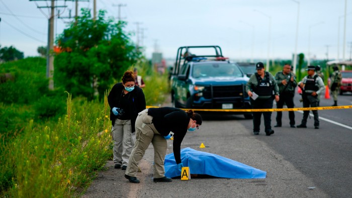 Investigadores de la escena del crimen trabajando luego de que se encontrara un cuerpo al costado de una carretera en Culiacán, estado de Sinaloa.